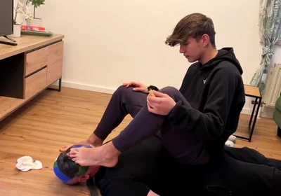 German master sitting on feet licking boy