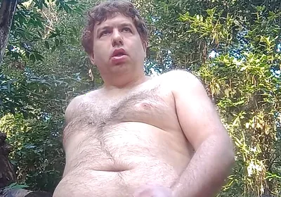 Boy in the woods sitting on a tree trunk pees and then jerks off with saliva coming from his mouth at the end